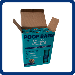An open cardboard box of Shabbee Dog Care unscented poop bags, showing teal plastic bags inside, on a white background with a blue border.