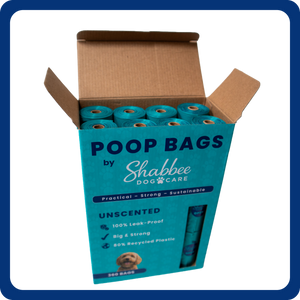 An open cardboard box of Shabbee Dog Care unscented poop bags, showing teal plastic bags inside, on a white background with a blue border.