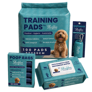 A dog training and grooming bundle by Shabbee Dog Care, including a large teal bag of training pads, a box of unscented poop bags, a pack of bamboo fibre grooming wipes, and a dispenser, all arranged on a white background with a small golden dog photo printed on the packaging.