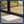 White training pad with blue border on a wooden floor in front of glass doors.